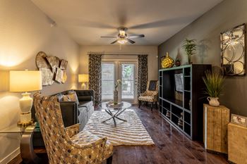 a living room with a ceiling fan and a door to a balcony